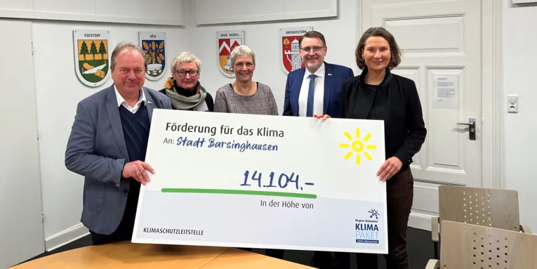 Symbolischer Scheck mit Fördersumme und eine Gruppe von Personen, die diesen halten